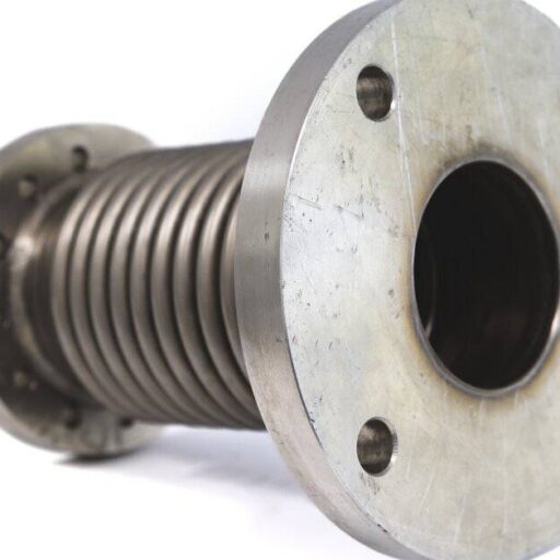 A gray metal expansion joint with flange end fittings sits on a white surface. The background behind the joint is white.